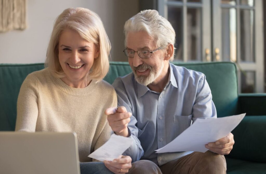 Two older adults research personal care, smiling and pointing excitedly at the screen.
