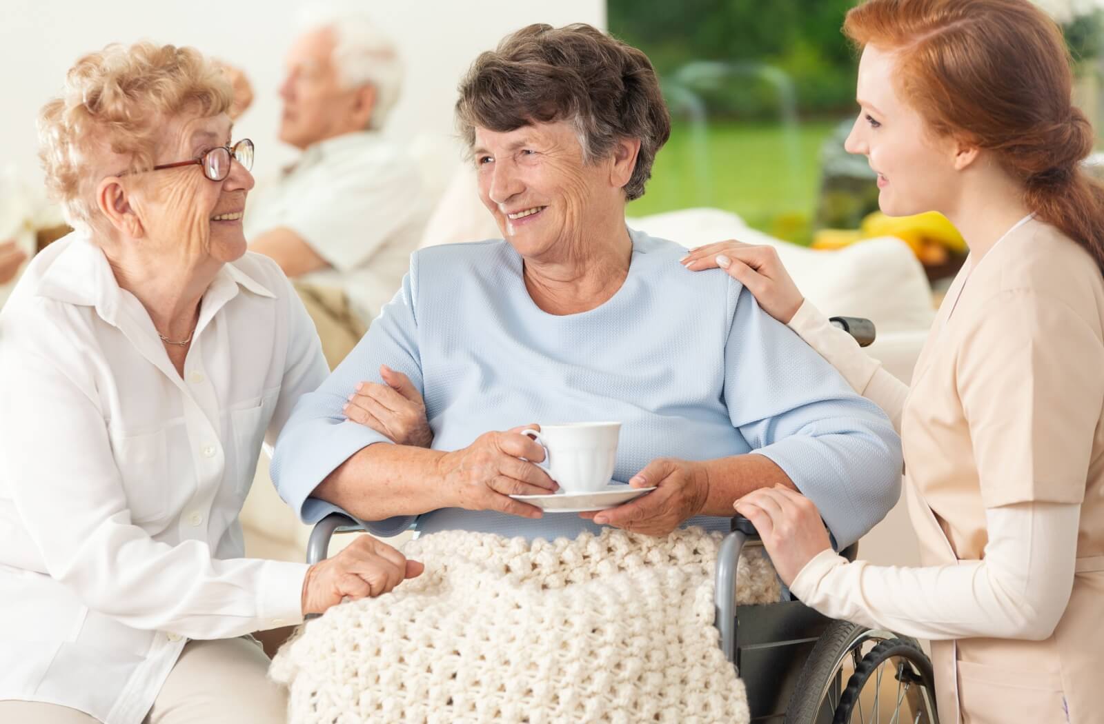 Someone receives coffee and a check in from a care provider at a senior living community.