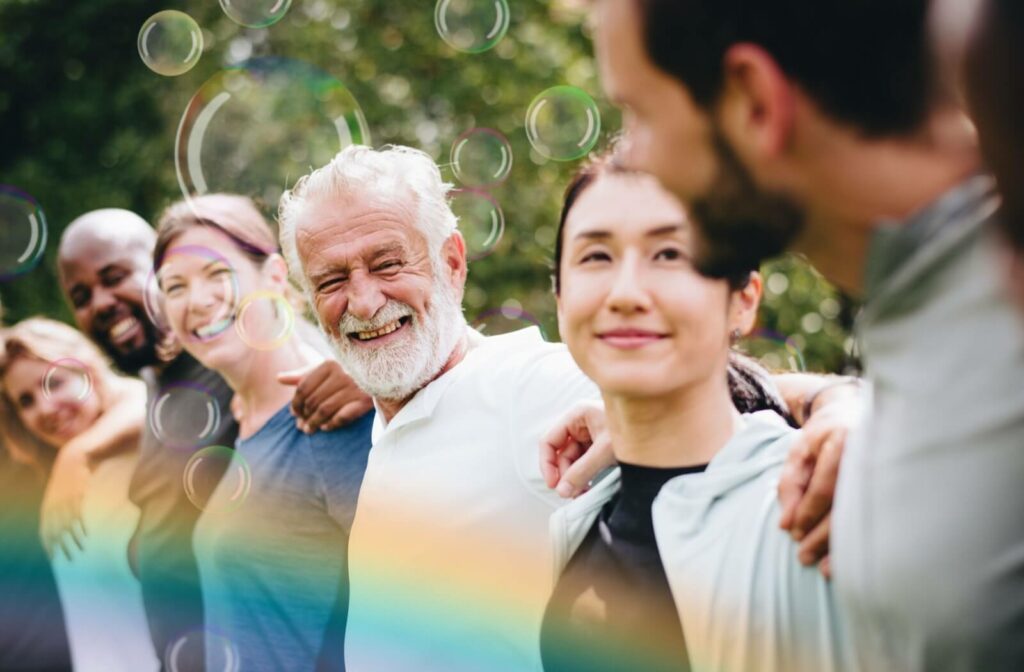 A group of adults and older adults stand in a line while outdoors, delighting in each other’s company